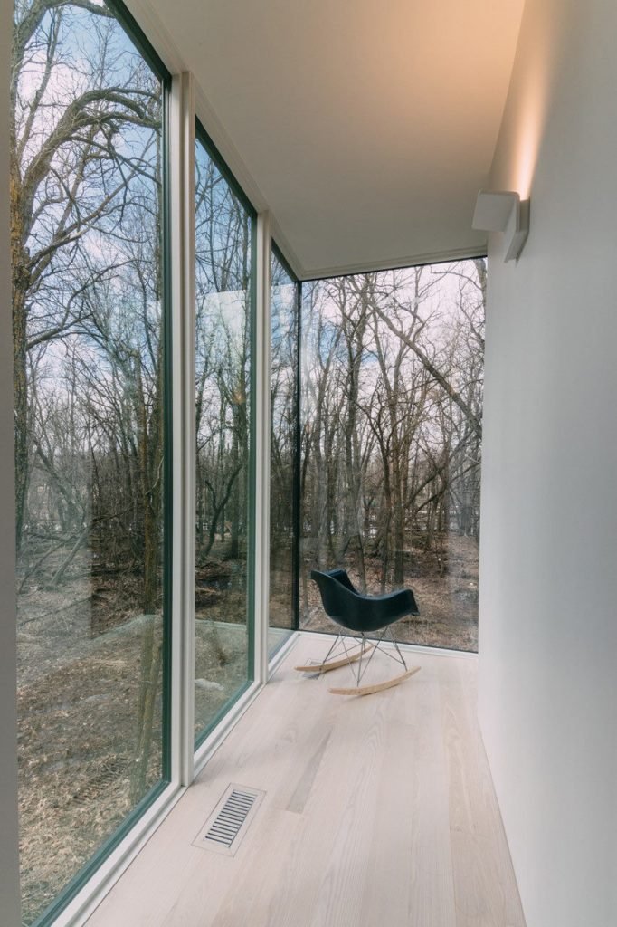 a room with a black rocking chair and large windows